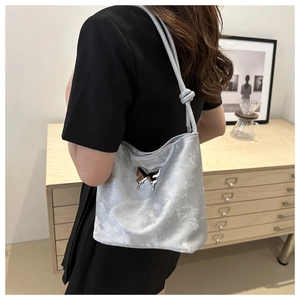 Détail du sac bandoulière argenté métallisé avec papillon et bandoulière nouée