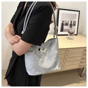 Détail du sac à épaule argenté métallisé avec logo papillon et lanières nouées
