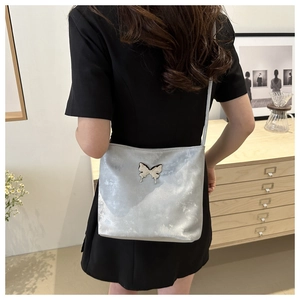 Sac seau argenté avec papillon métallique porté par un mannequin en robe noire