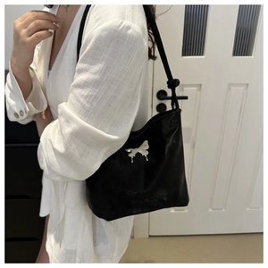 Détail de l'ornement papillon en métal argenté sur un sac à bandoulière en cuir noir mat