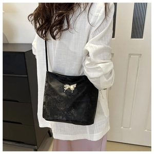Détail du sac cabas noir mat avec boucle papillon argentée et fine bandoulière