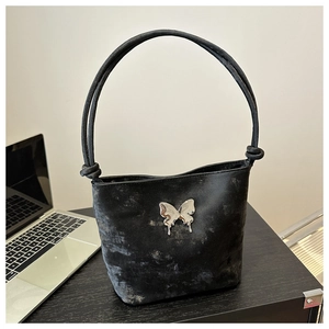Détail du sac seau noir métallisé avec boucle papillon argentée et bandoulières nouées