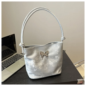 Sac seau argenté métallisé avec ornement papillon sur table en bois sombre