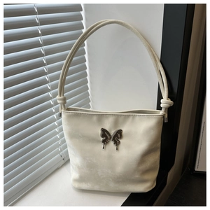 Détail du sac beige avec papillon en argent liquide et bandoulière à nœud tressé