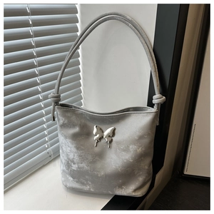 Vue détaillée d'un sac à bandoulière argenté avec décoration papillon et texture métal