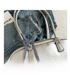 Detailed macro view of silver metallic wrinkled PU handbag with blue checkered ribbon bow