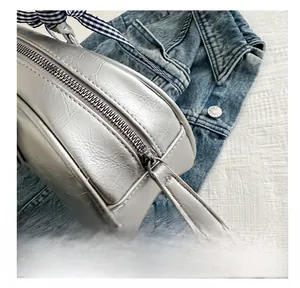 Detailed close-up of smooth silver metal zipper and decorative ribbon on stylish PU bag