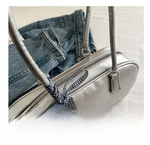 Detail of silver faux leather crossbody bag with vintage crackle texture and blue bow