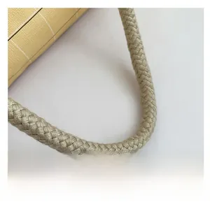 Detail of a beige tote bag featuring a durable braided shoulder strap and textured surface