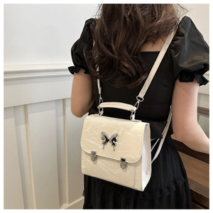 Detail of cream mini butterfly backpack with metallic accents on a model's back