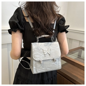Detail of silver pleated mini backpack with butterfly metal clasp worn by a model