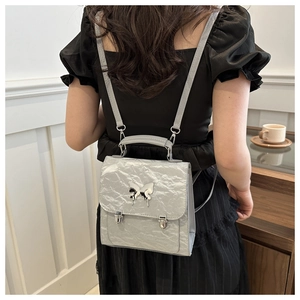 Silver wrinkled PU backpack detail with metallic butterfly ornament on a model