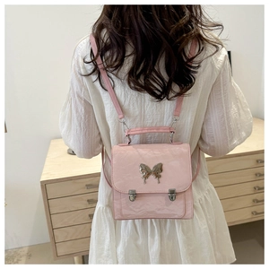 Pink glossy mini backpack with large silver butterfly buckle shown on model back
