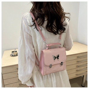 Detailed back view of a pink faux leather backpack with silver butterfly buckle and lychee grain
