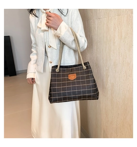 Close-up of classic check pattern tote bag with woven rope handles and leather detail