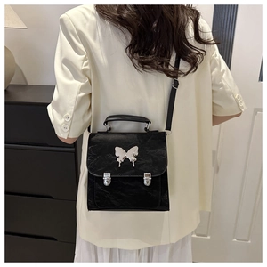 Detail of a black butterfly handbag with pleated texture and silver metallic buckle