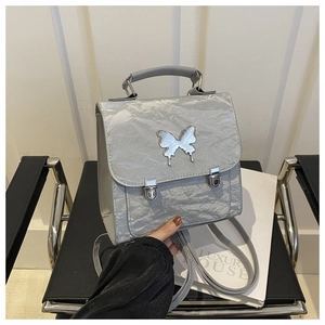 Detailed view of silver butterfly buckle on metallic pleated convertible backpack