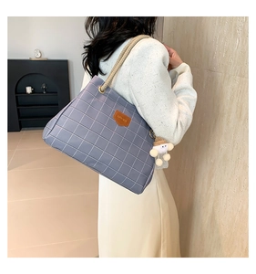 Detail of grid pattern tote bag with woven rope handle and brown leather brand tag