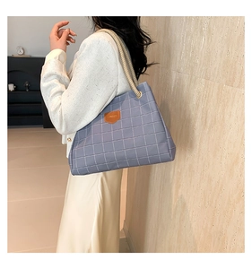 Detail of blue checkerboard tote bag with rope handles and brown leather patch