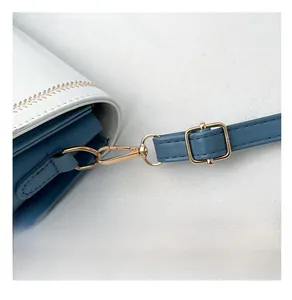 Detail of blue and white crossbody bag featuring gold wheat embroidery and premium hardware