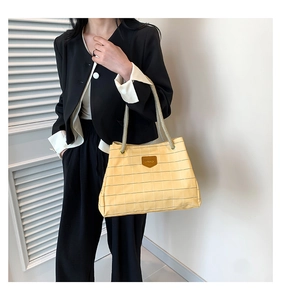 Detail of light yellow checkered tote bag with woven rope handle and leather logo tag