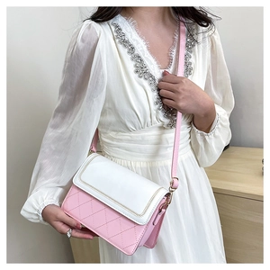 Detail of pink quilted pattern crossbody bag with golden buckle on white dress
