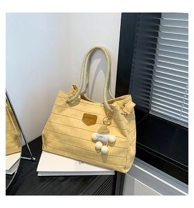 Detail of yellow checkered canvas tote bag featuring thick rope handles and plush charm