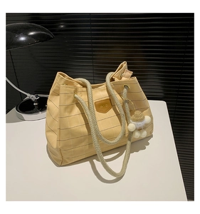 Close-up of yellow checkered canvas tote bag with thick rope handles and plush lamb charm