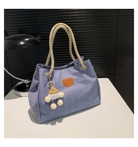 Detail of lavender checkered tote bag with hemp rope handles and a plush pompom charm