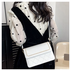 Close-up of white quilted crossbody bag featuring golden hardware and herringbone stitching