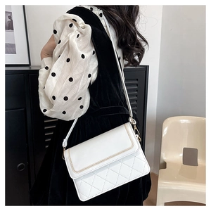 Close-up of white crossbody bag with classic diamond quilting and gold stitch detailing