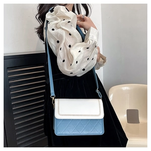 Blue and white quilted crossbody bag worn by a model in an elegant interior setting