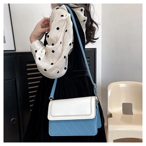 Detail of blue and white quilted crossbody bag with adjustable leather strap and stitching