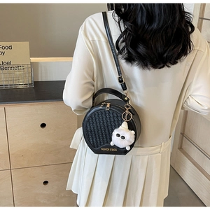 Detail der schwarzen runden Handtasche mit gewebter Textur und süßem Plüsch-Anhänger
