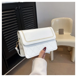 Detail of cream crossbody bag featuring quilted lattice pattern and gold hardware