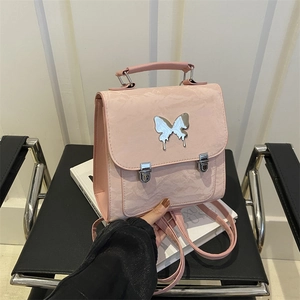 Pink vintage mini backpack with butterfly buckle on a black chair with books
