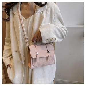 Close-up of pink crossbody bag with suede texture, leather flap and silver buckle detail
