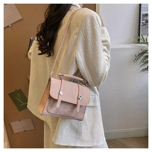 Close-up of pink crossbody bag with metal buckles shown on a white blazer outfit
