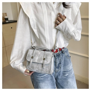 Detail of silver messenger bag with vintage texture and circular metal buckles