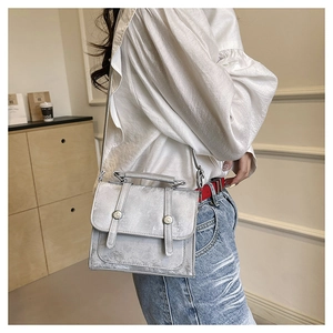 Detail of silver textured box bag with metallic twist lock shown on a model