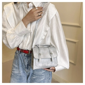 Detail of silver messenger bag with metal rivets and vintage texture on model