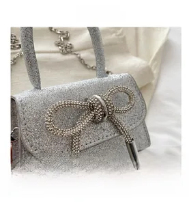 Détail du mini sac argenté scintillant avec une boucle de nœud en strass brillant