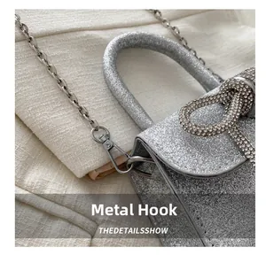 Détail macro d'un sac argenté scintillant avec nœud en strass et crochet en métal