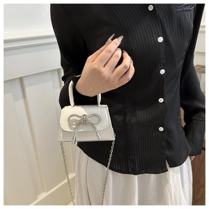 Detail of silver glitter mini handbag with a rhinestone bow and chain strap