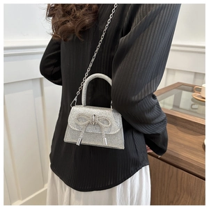 Detail showing glittery silver mini bag with rhinestone bow and silver chain strap