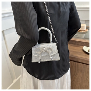 Mini sac argenté scintillant avec un grand nœud en strass porté par un mannequin