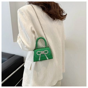 Mini sac vert pailleté avec nœud en strass et chaîne porté par un mannequin