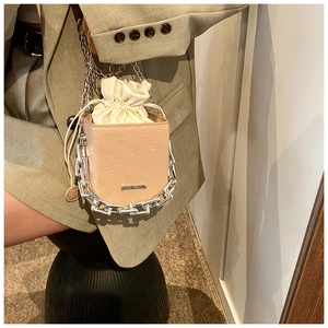 Detail of beige bucket bag with rich rabbit embossing and chunky silver chain strap