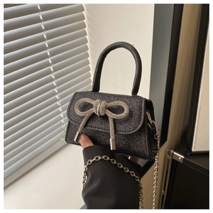 Détail du mini sac noir pailleté avec un grand nœud en strass argenté et chaîne