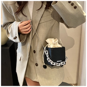 Detail showing black square bucket bag with cream drawstring liner and chunky silver chain